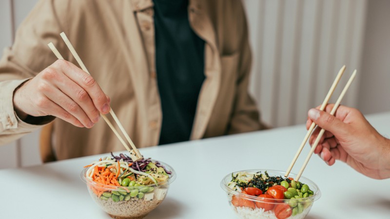 Close-up of two people enjoying healthy rice bowls with chopsticks, featuring fresh vegetables and rice., tags: für - pexel